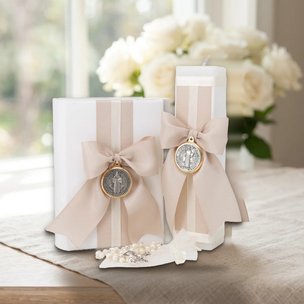 Kit Beige con moño y medalla San Benito sobre mesa con mantel de lino y rosas blancas – Casa Gala Puebla
